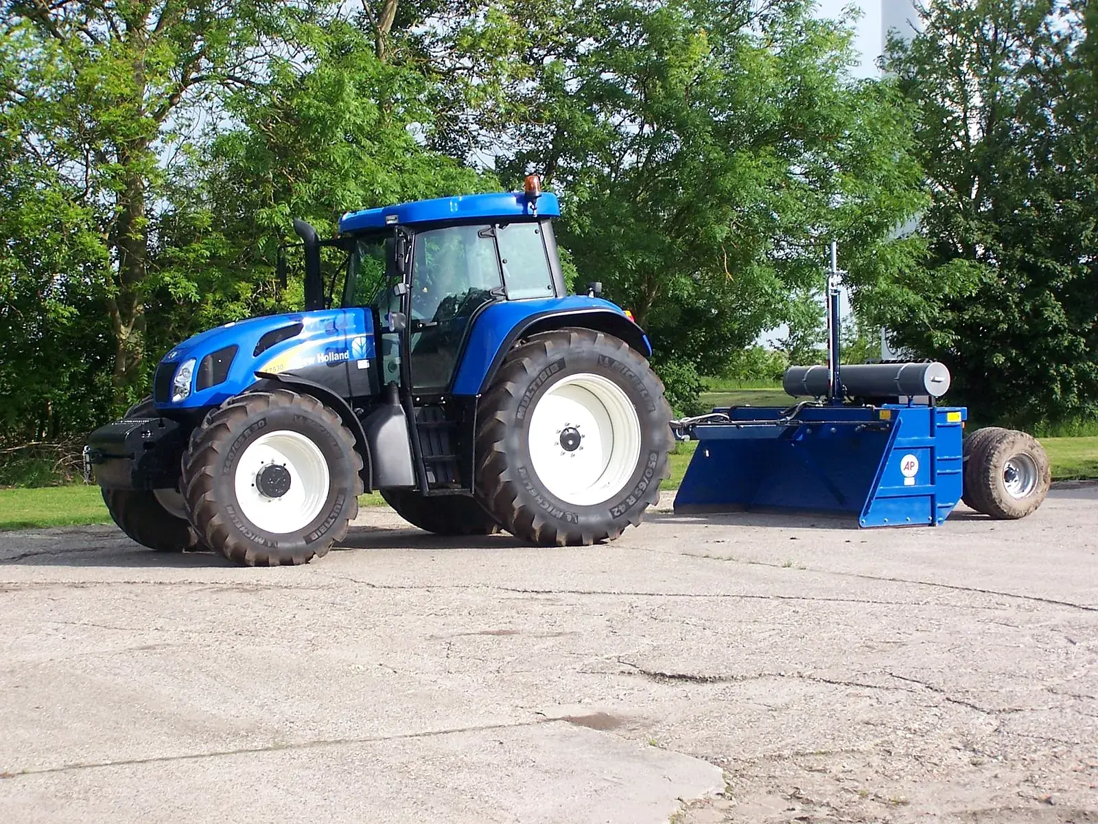 Blauwe AP kilverbak achter de New Holland trekken op het erf in Creil